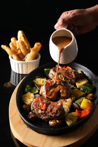 a plate of food with meat and vegetables and sauce at Somerset Mirissa Blue in Mirissa