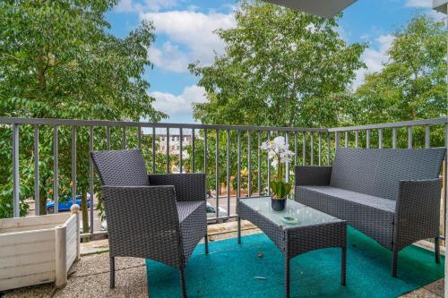 a patio with two chairs and a table with flowers at Appart Standing in Trappes