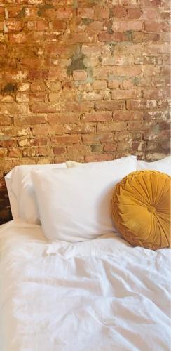 a bed with a pillow on it with a brick wall at Mordern Lil' Love Nest Loft in Midrand in Midrand