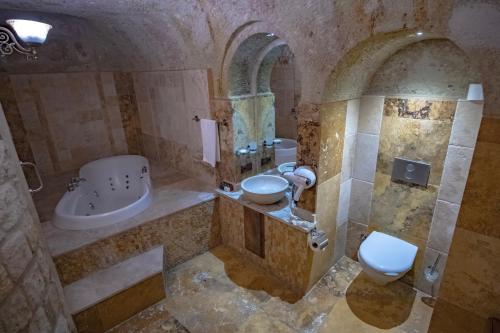 a stone bathroom with a sink and a toilet at Kemerhan Cave Suites in Urgup