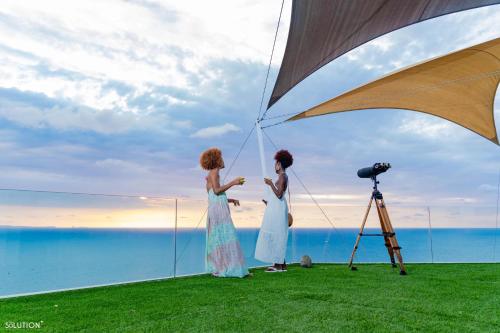 two women in dresses standing in front of a camera at La Canopée vue sur mer in Nosy Be