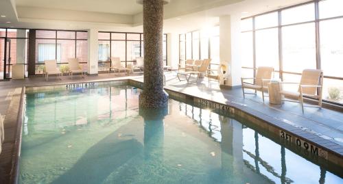 a pool with chairs and a palm tree in a building at Holiday Inn Express & Suites Oklahoma City Downtown - Bricktown by IHG in Oklahoma City