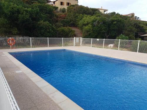 une piscine bleue en face d'une clôture dans l'établissement La Perle du Valinco #Familial#Balcon#Piscine#Mer, à Propriano