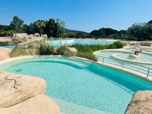 une grande piscine dans un parc aquatique avec des rochers dans l'établissement Les Restanques du Golfe de Saint Tropez Außergewöhnlicher Meerblick TOP WLAN, à Grimaud