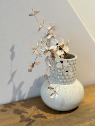 a white vase with flowers in it on a table at Stadthäuschen in Kitzingen in Kitzingen