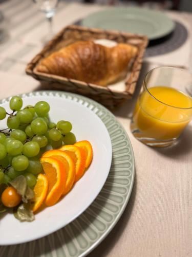 a table with a plate of grapes and oranges and a glass of orange juice at Stadthäuschen in Kitzingen in Kitzingen