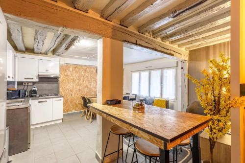 une cuisine et une salle à manger avec une grande table en bois dans l'établissement Maison Hyper Centre Rouen - Patio - TV 4K - WIFI-Fibre - 4 chambres - Machine à laver - Sèche linge - Lave Vaisselle - Confort - Spacieux, à Rouen