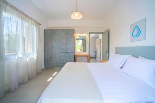 a bedroom with a large white bed and a window at Elounda Garden Maxima Suite Beheiztes Schwimmbad in Elounda
