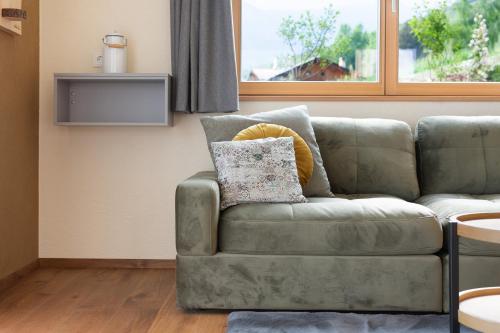 a green couch in a living room with a window at Ratscheinerhof App Gipfelglück in Lazfons