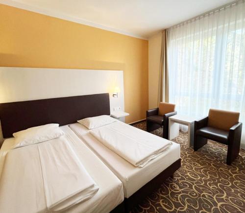 a hotel room with a large bed and two chairs at Parkhotel Green Garden in Bad Hersfeld