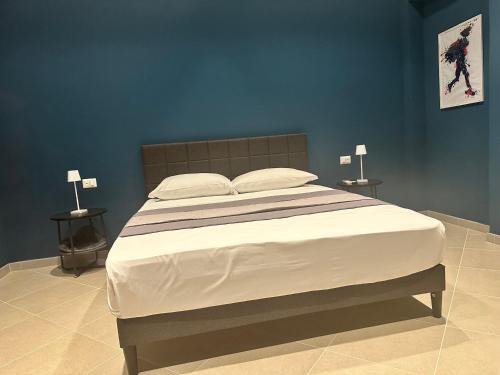 a bedroom with a large bed with blue walls at Sunset Palace Guesthouse in Reggio Calabria