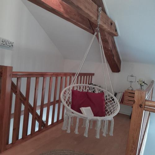 a hanging chair with a red pillow in a room at Gîte NOCTUA chez Gîtes QUE CANTA in Saint-Julien-Vocance