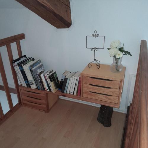 a book shelf with books and a vase of flowers at Gîte NOCTUA chez Gîtes QUE CANTA in Saint-Julien-Vocance