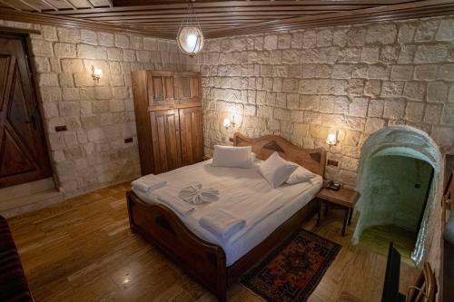 a bedroom with a bed and a stone wall at Kemerhan Cave Suites in Urgup