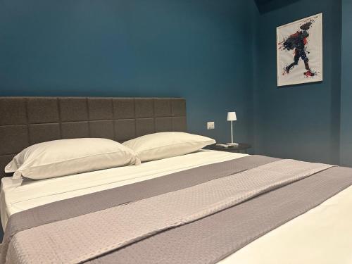 a large bed in a bedroom with a blue wall at Sunset Palace Guesthouse in Reggio Calabria