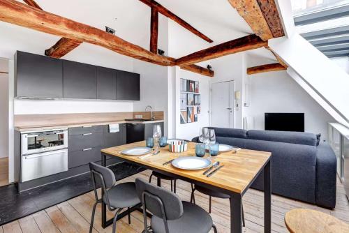 une cuisine et une salle à manger avec une table et des chaises en bois dans l'établissement BM-Un Eclat de Lumiere en Plein Paris, à Paris