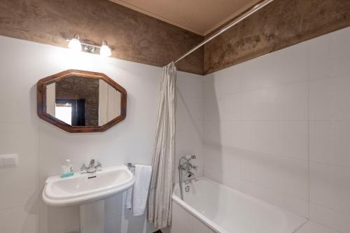 a bathroom with a sink and a tub and a mirror at El Baluard De Ferreres in Olvan