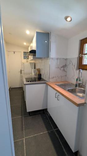une petite cuisine avec des armoires blanches et un évier dans l'établissement Appartement cosy 4 pers Drancy, à Drancy