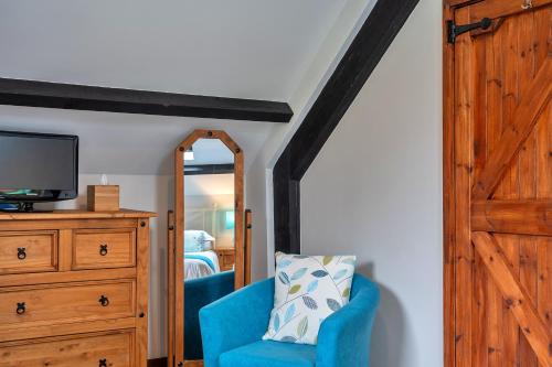 a bedroom with a blue chair and a mirror at Finest Retreats - Chasty House Barn in Holsworthy
