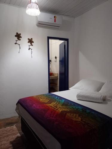a bedroom with a bed with a colorful blanket at CASA TRILHAS DE IGATU - CHAPADA DIAMANTINA - BAHIA in Igatu
