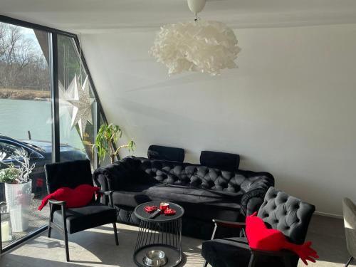 a living room with a black couch and chairs at LaKadisa pe Lac in Porumbacu de Jos