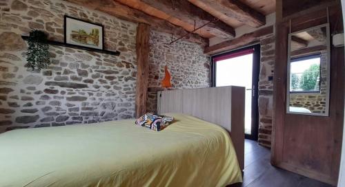 une chambre avec un lit et un mur en pierre dans l'établissement Charmante maison de campagne, à Yvignac