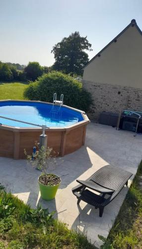 une terrasse avec une piscine, une chaise et une table dans l'établissement Charmante maison de campagne, à Yvignac