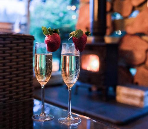 two glasses of champagne with strawberries in them on a bar at Loch Lomond Hideaways- Luxury Cabins with Jacuzzis in Drymen