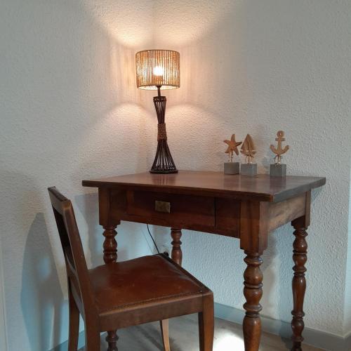 a table with a lamp and a chair with a lamp at Gîte NOCTUA chez Gîtes QUE CANTA in Saint-Julien-Vocance