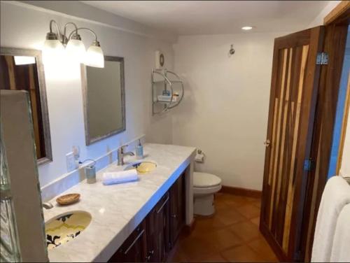 Un baño con lavabo, inodoro y espejo. en 2 min walk to Medano Beach-Marina Huge pool Cozy, en Cabo San Lucas