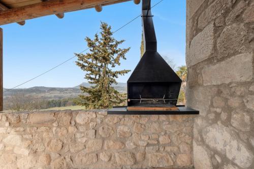 a fireplace in a stone wall with a tree in the background at El Baluard De Ferreres in Olvan