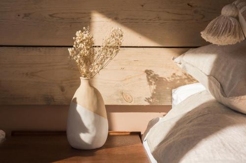 a white vase sitting on a table next to a bed at Du Cabana By Birch Stays in Rhosneigr
