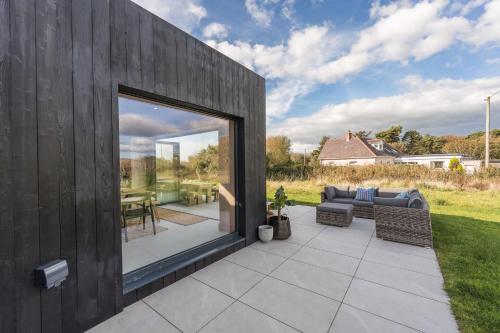 a patio with a large window and a couch at Du Cabana By Birch Stays in Rhosneigr