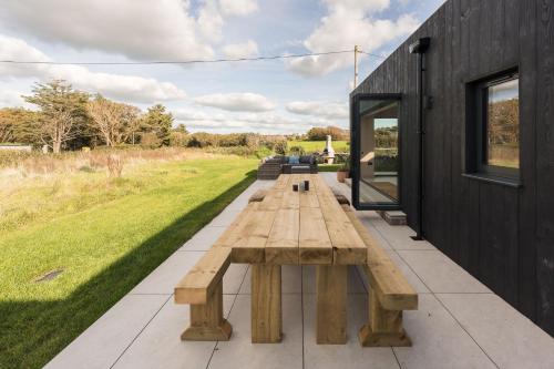 a wooden table on a patio with a bench at Du Cabana By Birch Stays in Rhosneigr