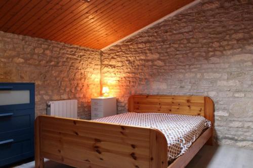 - une chambre avec un lit en bois dans un mur de briques dans l'établissement Maison 3 pièce 5 couchages Saint Pierre d'Oléron SPO000-003, à Saint-Pierre-dʼOléron