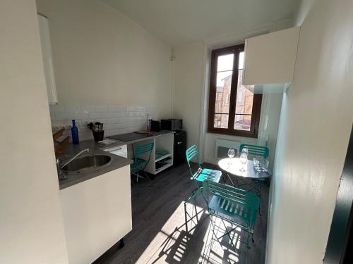 - une cuisine avec un évier, une table et des chaises dans l'établissement Appartement cosy, à Chessy