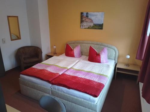 a bedroom with a bed with red and pink pillows at Pension Tiffany in Chemnitz