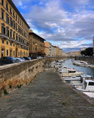 a canal with boats in a city with buildings at Cozy Stay in City Center in Livorno