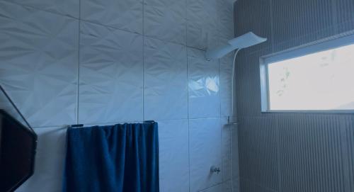a bathroom with a blue shower curtain and a window at CASa LUAR DA BARRA in Barra dos Coqueiros