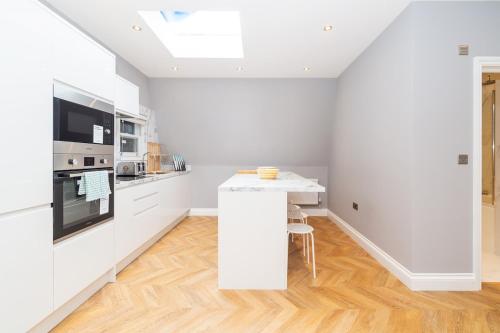 a kitchen with white cabinets and a white counter top at Modern Two-Bedroom Apartment in Paddington in London