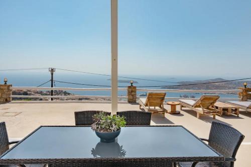 a table and chairs on a patio with a view of the ocean at Κατοικία Uppolis με θέα τα νησιά in Ano Syros