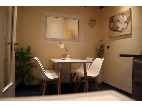a table with white chairs and a table with a flower on it at Gästehaus Elzblick in Rust