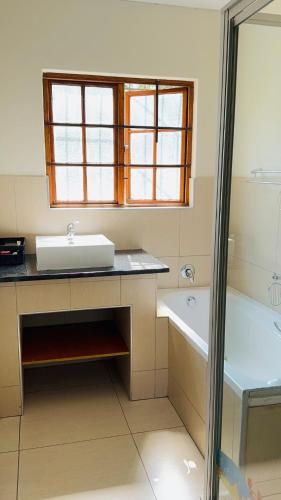 a bathroom with a sink and a tub and a window at Home 11 Strydom in Nelspruit