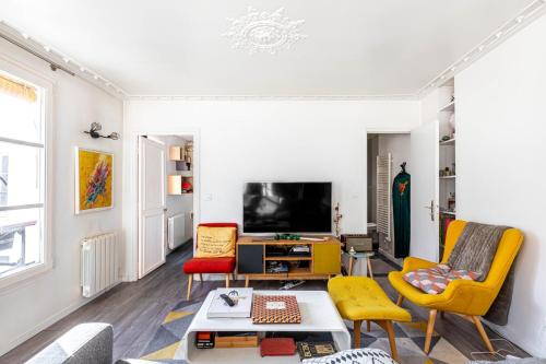 d'un salon avec des chaises jaunes et une télévision. dans l'établissement GuestReady - Elevated Charm near Notre-Dame, à Paris