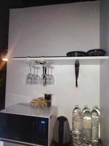 a shelf above a microwave with glasses on it at ONEWAY Guest House BKK in Bangkok