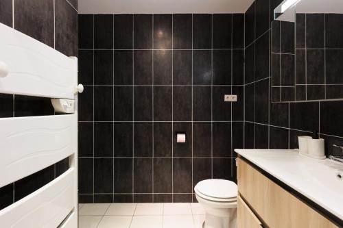 La salle de bains est pourvue de carrelage noir, de toilettes et d'un lavabo. dans l'établissement L'Azuréa - Centre - Plage - Wifi - Climatisation, à Cannes