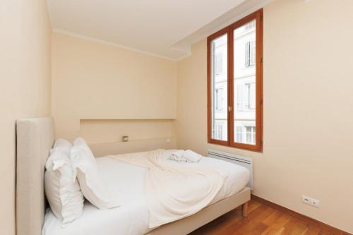 un lit blanc dans une chambre avec une fenêtre dans l'établissement L'Azuréa - Centre - Plage - Wifi - Climatisation, à Cannes