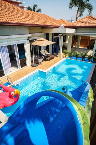 a pool with a water slide in front of a house at King Family Massarossa Pool Villa Pattaya VIP in Pattaya