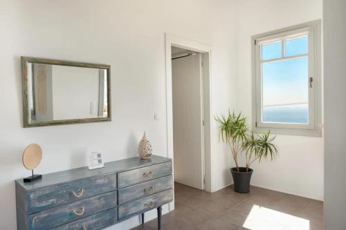 a room with a dresser and a mirror and a window at Κατοικία Uppolis με θέα τα νησιά in Ano Syros