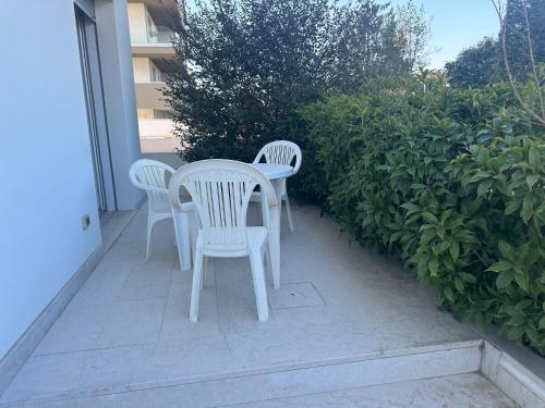 two white chairs and a table on a patio at Residence Antares - Agenzia Cocal in Caorle